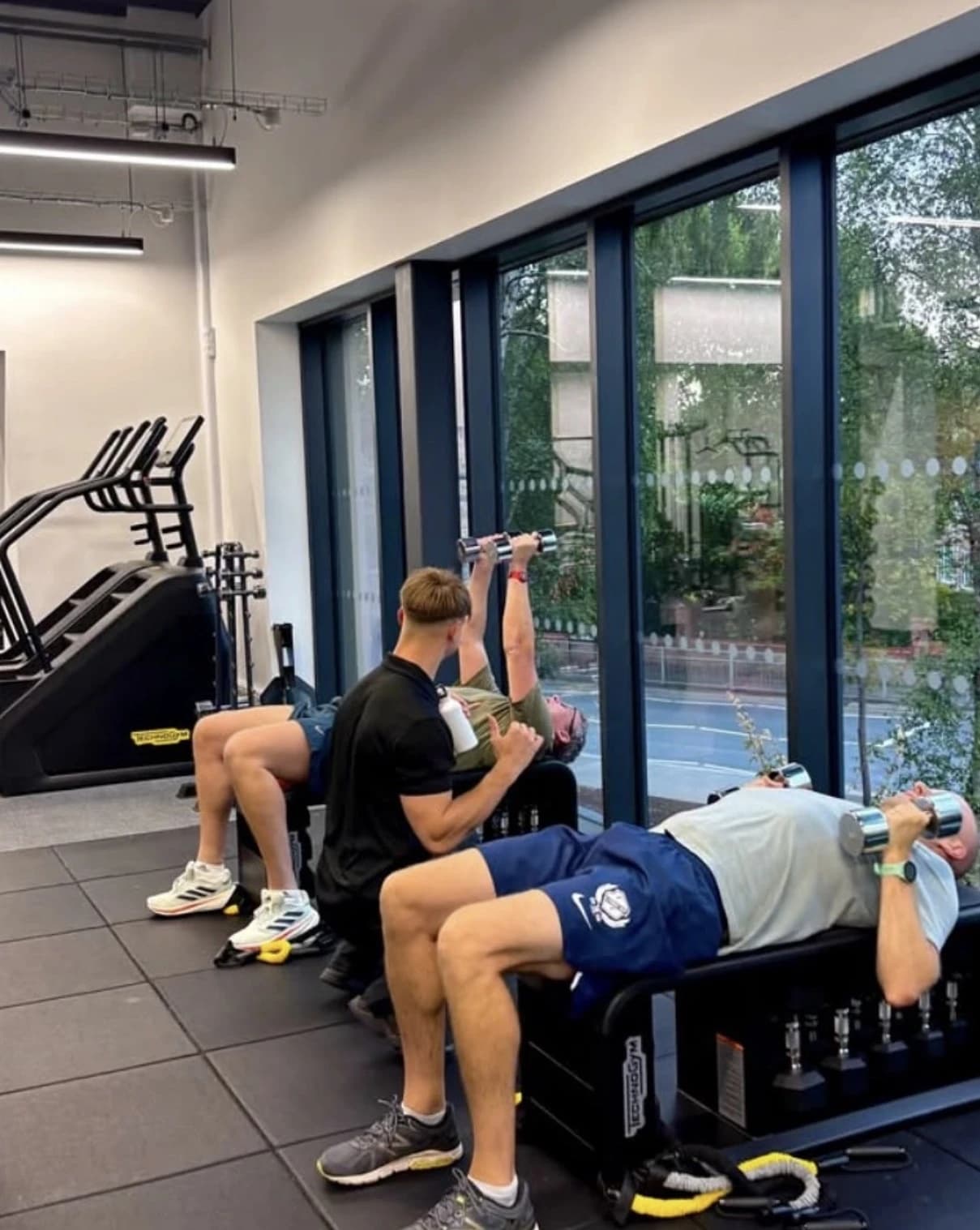 Kyle coaching a client through a dumbbell exercise in the gym